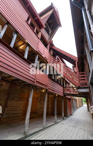 Bergen, Norwegen - 8. August 2022: Historische Holzgebäude von Bryggen in Bergen, Norwegen, aus einer engen Gasse gefangen genommen. Die roten Fassaden und Altholz Stockfoto