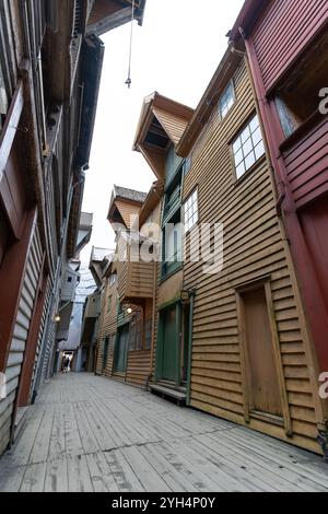 Bergen, Norwegen - 8. August 2022: Enge Gasse zwischen den ikonischen Holzhäusern von Bryggen in Bergen, Norwegen. Die historischen Gebäude mit malerischem qu Stockfoto