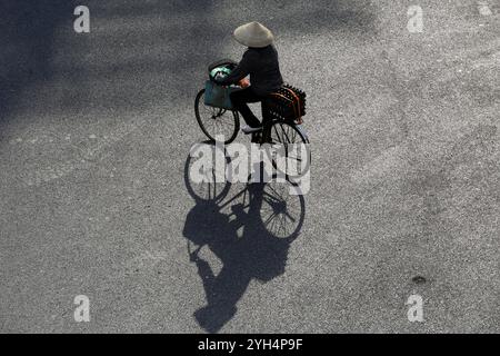 Die vietnamesische Frau trägt einen konischen Hut, der als Non La bekannt ist und das Gesicht während einer extremen Hitzewelle in Hanoi, Vietnam, vor der heißen Sonne schützt. Stockfoto