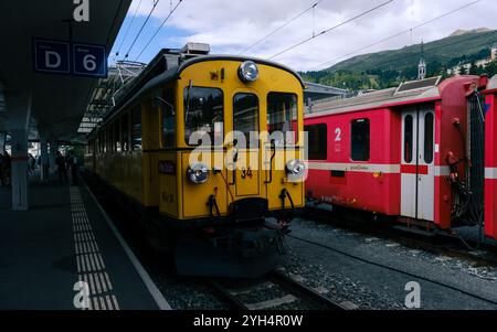 St. Moritz, Schweiz 11. August 2021: Eine pulsierende Sommerszene am Bahnhof St. Moritz mit alten gelben und roten Zügen, die sich gegen den malerischen Südwesten stellen Stockfoto