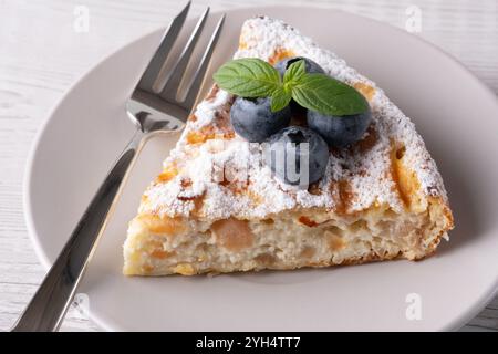 Köstliches Stück Kuchen mit frischen Heidelbeeren und einer Erdbeere auf einem hellen Holztisch Stockfoto