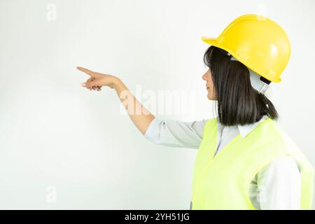 Architektin oder Ingenieurin, die einen Industriehelm trägt und mit dem Finger zeigt. Isoliertes Frauenporträt. Stockfoto