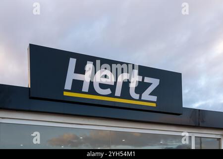 Nahaufnahme des Hertz-Logoschildes am Gebäude, das am frühen Morgen in der Autovermietung am Flughafen zu sehen ist Stockfoto