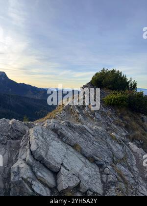 Sonnenuntergang über dem Tatra-Gebirge in Polen, der einen warmen Glanz auf den zerklüfteten Gipfeln und der dramatischen Landschaft ausstrahlt Stockfoto