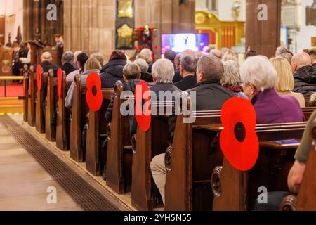 Warrington, Cheshire, England, Großbritannien. November 2024. Das jährliche Festival of Remembrance findet in der St. Elphin's Parish Church statt. Es war ein Abend, um an den Dienst und die Opfer unserer Streitkräfte in weltweiten Konflikten zu erinnern und zu ehren. Große rote Mohnblumen sind am Ende der Bänke für den Service angebracht. Quelle: John Hopkins/Alamy Live News Stockfoto