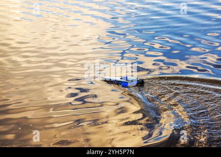 Ferngesteuertes Boot auf schimmernder Oberfläche des Sees. Stockfoto