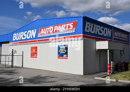 Sonnendurchflutetes Äußere eines Burson Auto Parts Stores mit weiß-, Blau- und Rot-Branding, das an einem sonnigen Tag an der Seite des Gebäudes hell beleuchtet wird Stockfoto