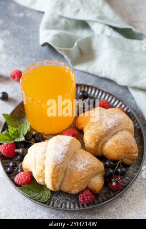 Leckere frisch gebackene Croissants und Orangensaft auf grauem Stein Hintergrund, Frühstückskonzept. Dessert französisches Gebäck. Stockfoto
