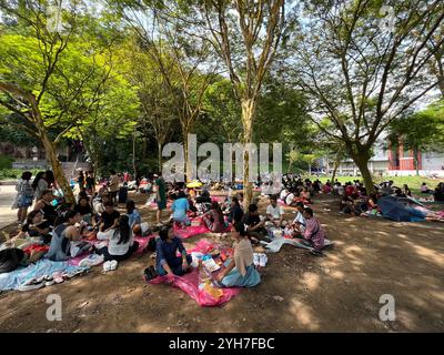 Große Zusammenkunft einheimischer ausländischer Arbeiter auf dem Feld, die ihren Sonntagstag genießen. Picknick machen, entspannen, Freunde treffen. Singapur. Stockfoto