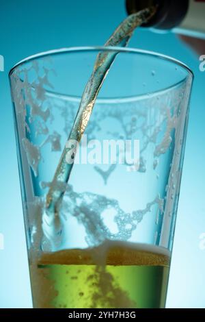 Bier gießen, Strom von leichtem Bier. Fassbier in einem Glas auf blauem Hintergrund. Selektiver Fokus Stockfoto