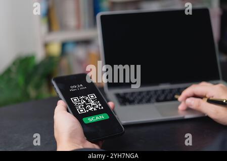 Hand hält Smartphone mit QR-Code auf dem Bildschirm, bereit zum Scannen. Perfekt für digitale Zahlungen, E-Commerce und Fintech-Lösungen. Stockfoto