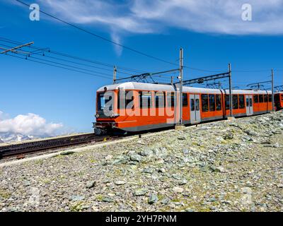 Roter Touristenzug auf Gornergrat-Bahn in der Nähe des Matterhorns auf blauem Himmel Hintergrund am sonnigen Tag, Sommersaison in den Schweizer Alpen, Touristenziel in Stockfoto