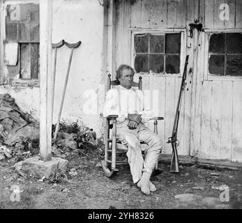 John L. Burns, der „alte Held von Gettysburg“, 69 Jahre alt, mit seinem Gewehr und zwei Krücken, die am 15. Juli 1863 hinter ihm standen, in Gettysburg, Pennsylvania. Fotografiert von Timothy H. O'Sullivan. Eine Kombination zweier Stereogramme von feuchten Kollodionnegativen. Stockfoto