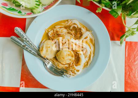 Thailändische Reisnudeln in Fisch-Curry-Sauce mit Zutaten auf dem Tisch. Stockfoto