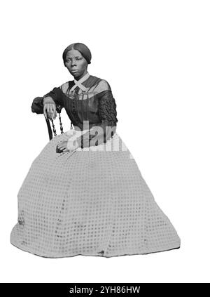 Eine Carte-de-Visite von Harriet Tubman (ca. 46-47) in den Jahren 1868-69. Sie sitzt, nach links gedreht. Eine Hand liegt auf der Rückseite eines Holzstuhls, eine andere auf ihrem Schoß. Erstellt von Benjamin Powelson, 77 Genesee St., Auburn, New York. Harriet Tubman saß in einem Innenraum. Sie ist leicht nach rechts gedreht und blickt von der Kamera ab. Ihre rechte Hand liegt auf der Rückseite eines Holzstuhls und ihre linke Hand auf ihrem Schoß. Ein kühn gemusterter Teppich bedeckt den Boden und die Wand oder fällt hinter ihr in einer leeren hellen Farbe. Tubman trägt ein schwarzes Mieder, das vorne in der Mitte Knöpfe und Stockfoto