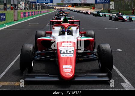 Rot-weißes Formel-Auto wartet an der Startlinie einer Rennstrecke, andere Autos stehen hinter ihr Stockfoto