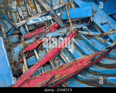 Der Boden eines alten, kaputten, hölzernen Bootes mit abblätternder blauer und roter Farbe Stockfoto