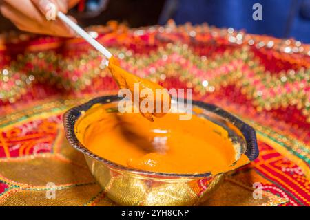 Indische Haldi-Zeremonie vor der Hochzeit mit gelber Paste in einer Schüssel – traditionelles Hautpflegeritual Stockfoto