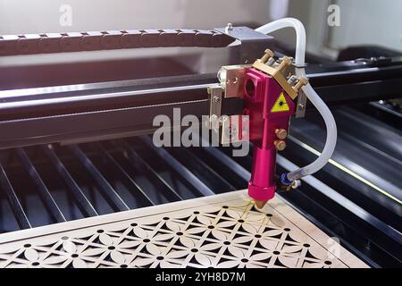 Lasergravurmaschine schneidet ein Design auf eine Holzoberfläche. Industrie Stockfoto