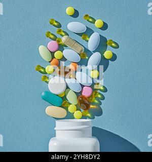 Verschiedene farbenfrohe Pillen und Kapseln und weiße Flasche auf blauem Hintergrund, Draufsicht Stockfoto