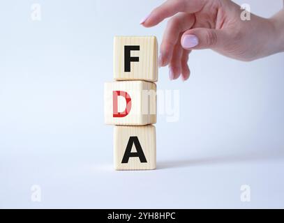 FDA – Symbol für die Arzneimittelverwaltung. Holzwürfel mit Wort FDA. Arzthand. Schöner weißer Hintergrund. Medizinische und Food Drug Administration Conce Stockfoto