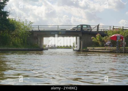 Ludham Bridge, über den Fluss Ant in der Nähe von Ludham, Norfolk, Broads National Park - mit einem Auto über, einem Boot unter und Anglern am Ufer. Stockfoto