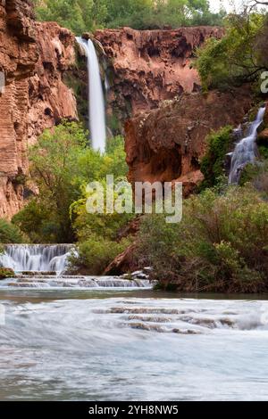 Die Mooney Falls ergießen sich hoch über dem Havasu Creek in der Ferne. Havasupai Reservation, Arizona Stockfoto