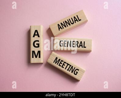 Jahreshauptversammlung – Symbol für Jahreshauptversammlung. Konzeptwort AGM auf Holzblöcken. Schöner rosafarbener Hintergrund. Business- und NGM-Konzept. Kopierbereich. Stockfoto