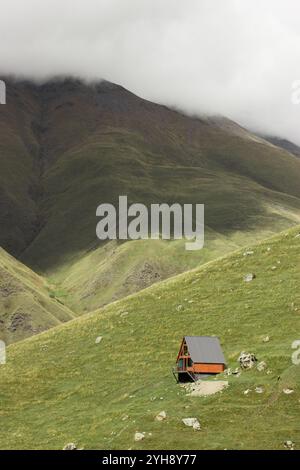 Dieses vertikal ausgerichtete Foto fängt die ruhige Schönheit der georgischen Landschaft im Herbst ein. Eine kleine Holzkabine mit einer dreieckigen Dachauflage Stockfoto