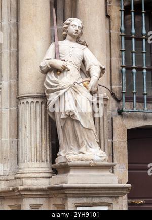 Auf einem Gebäude in Pamplona steht eine anmutige Statue, die eine Frau mit Schwert und Waage darstellt, die Gerechtigkeit symbolisiert. Stockfoto