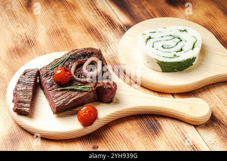 Mittelseltenes Rindersteak mit Kirschtomaten und Käse- und Kräuterbrötchen auf Holzbrett und Hintergrund. Hochwertige Fotos Stockfoto