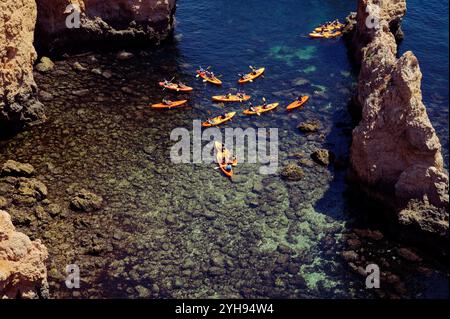 Eine Gruppe von Kajakfahrern paddelt durch klares Wasser rund um die Felsformationen von Ponta da Piedade Stockfoto