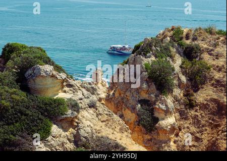 Das Boot gleitet entlang des türkisfarbenen Wassers vor den Klippen von Ponta da Piedade Stockfoto