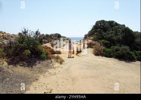 Frau, die an Ponta da Piedade entlang eines malerischen Küstenweges in Richtung Atlantik schlendert Stockfoto