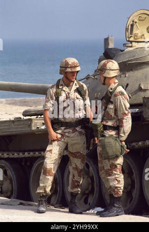 Erster Golfkrieg: 10. März 1991 Soldaten der US-Armee stehen neben einem verlassenen irakischen Typ 69 Panzer in seiner Sandsäcke am Anjafa Beach in Kuwait City. Stockfoto