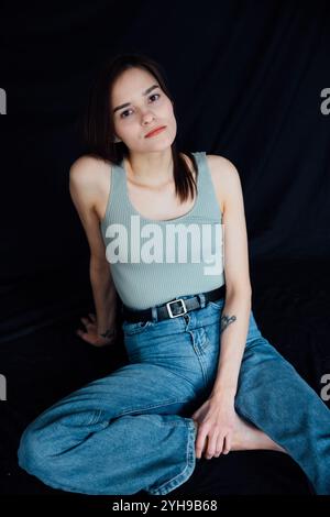 Porträt der schönen schlanken Frau in Jeans auf schwarzem Hintergrund Stockfoto