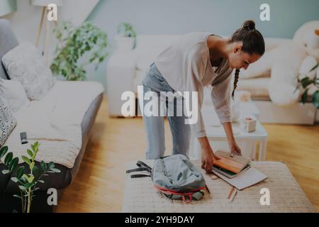 Junge Studentin organisiert Studienmaterialien zu Hause Stockfoto