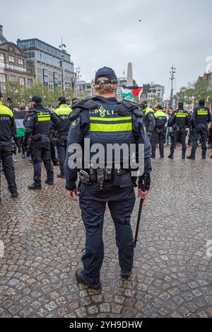 Amsterdam, Nordholland, Niederlande. November 2024. Ein niederländischer Polizist steht mit dem Stab in der Hand vor einer großen Gruppe von Demonstranten. Am 10. November 2024 hielten Demonstranten in den Niederlanden einen unerlaubten Protest auf dem Dam-Platz in Amsterdam ab. Dies geschah als Reaktion auf die Bezeichnung eines Protests vom 7. November, der gewalttätig als antisemitisch wurde, und das anschließende vorübergehende Verbot von Protesten in Amsterdam. (Kreditbild: © James Petermeier/ZUMA Press Wire) NUR REDAKTIONELLE VERWENDUNG! Nicht für kommerzielle ZWECKE! Quelle: ZUMA Press, Inc./Alamy Live News Stockfoto