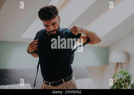 Mann, der sich auf die Reise vorbereitet, indem er einen Rucksack in einem gemütlichen Zimmer anzieht Stockfoto