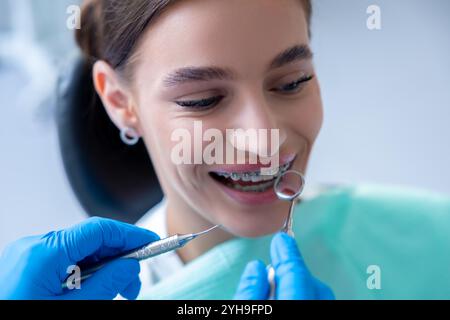 Schöne Frau, die in der Zahnarztpraxis untersucht wird, während der Zahnarzt ihre Zahnspange überprüft Stockfoto