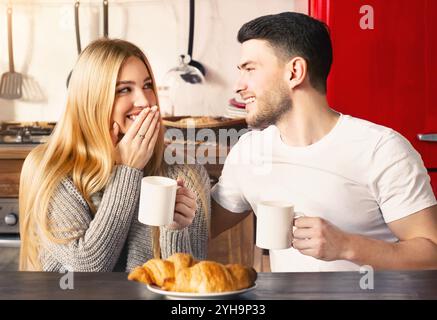 Süße Freundin und Freundin mit Kaffee und Croissants zum Frühstück in der Küche Stockfoto