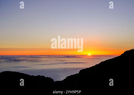 Ein atemberaubender Blick auf einen Sonnenaufgang über dem Meer. Die warmen Farben der aufgehenden Sonne erhellen den Himmel in sanften Verläufen von Orange, Gelb und Violett. Stockfoto