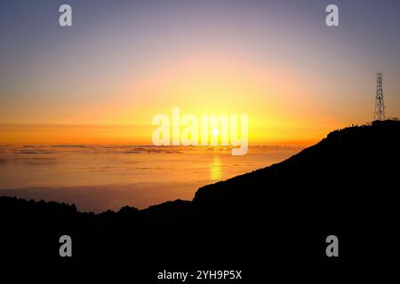Ein atemberaubender Blick auf einen Sonnenaufgang über dem Meer, während die Sonne einen warmen Glanz über den Horizont wirft. Stockfoto