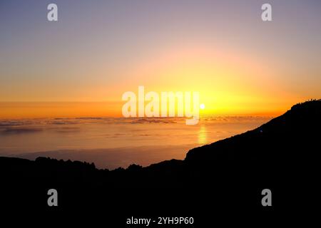 Ein atemberaubender Sonnenaufgang über dem Meer mit warmen Gelb- und Orangentönen. Die Sonne steht direkt über dem Horizont und strahlt ein goldenes Leuchten über die Landschaft. Stockfoto