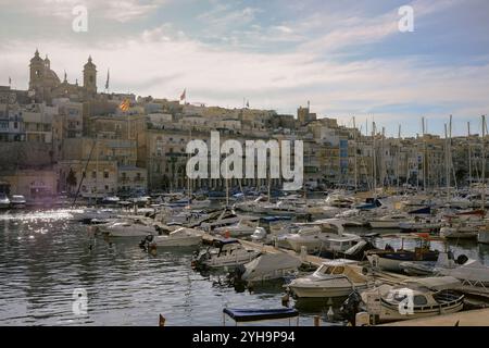 Senglea - Ein malerischer Yachthafen in Malta, mit einer Ansammlung von Booten, die entlang des ruhigen Wassers angedockt sind, eingerahmt von den bezaubernden Stadtgebäuden. Stockfoto