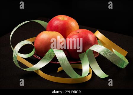 Rote Äpfel auf schwarzem Hintergrund mit Farbbändern Stockfoto