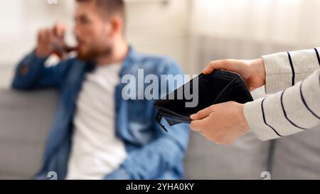 Frau mit leerer Brieftasche, betrunkener Mann alkoholisch im Hintergrund Stockfoto