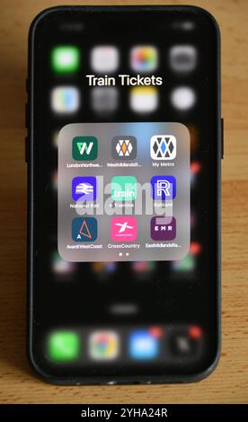 Britisches Smartphone auf dem Tisch mit Zugtickets-Anwendungen in einem Ordner für Bahnbetreiber, National Rail, Railcard und die Trainline.com Stockfoto
