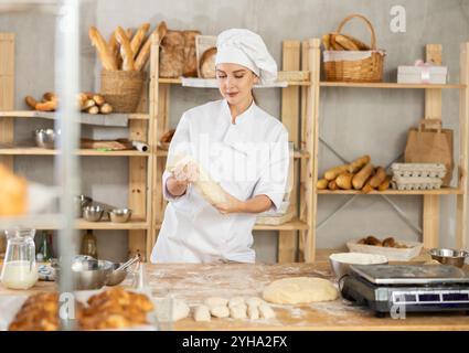Prozess der Herstellung von Baguette, Brot oder Brot in der Bäckerei - weibliche Bäckerinnen kneten und bröckeln Teig, um zukünftige Brote zu Formen Stockfoto