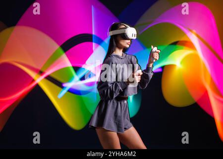 VR-, AR-, MR-, XR-Zukunftstechnologien. Neon. Ein junges Mädchen in einer VR-Brille in Neon, das Sport macht und ein Spiel spielt. Konzept moderner Gadgets und Technologien Stockfoto